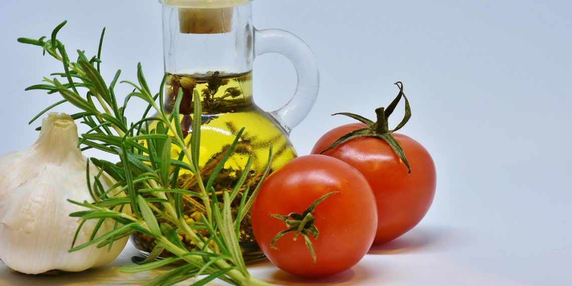 Garlic, rosemary, tomatoes, and olive oil arranged together.