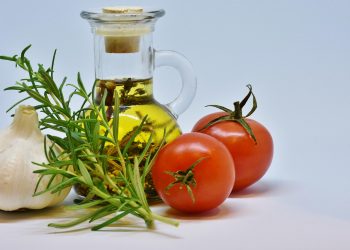 Garlic, rosemary, tomatoes, and olive oil arranged together.