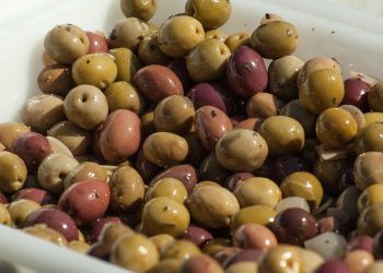 Various marinated olives in a tray, showcasing colorful Mediterranean varieties.