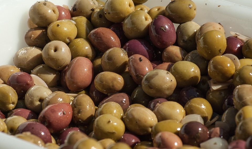 Various marinated olives in a tray, showcasing colorful Mediterranean varieties.