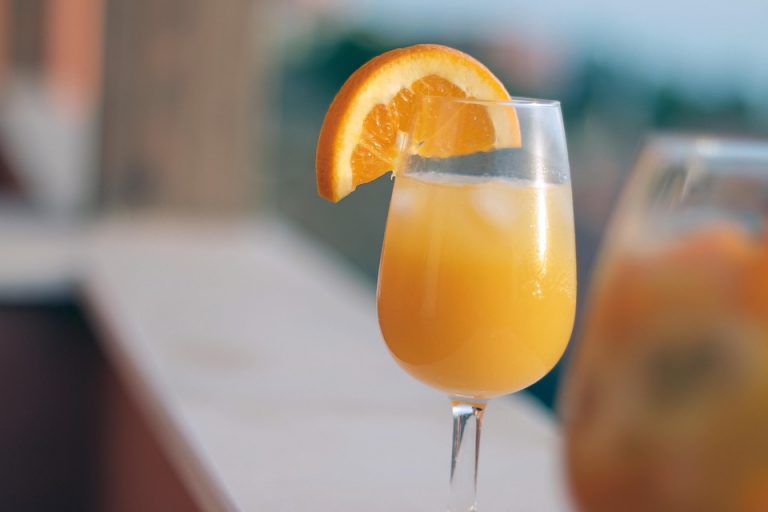 Orange juice cocktail with slice garnish, refreshing summer drink.