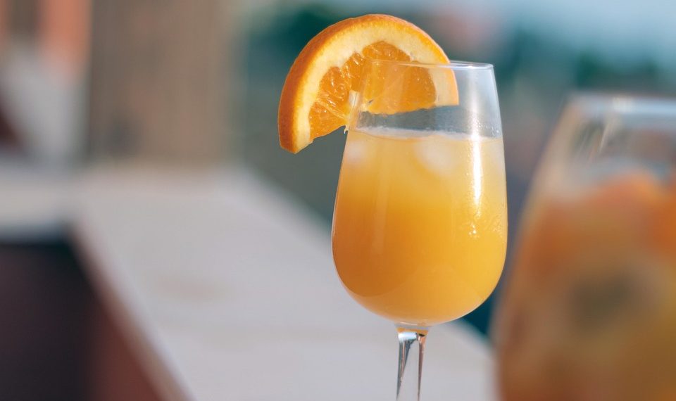 Orange juice cocktail with slice garnish, refreshing summer drink.