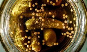 Pickles and mustard seeds in brine jar.