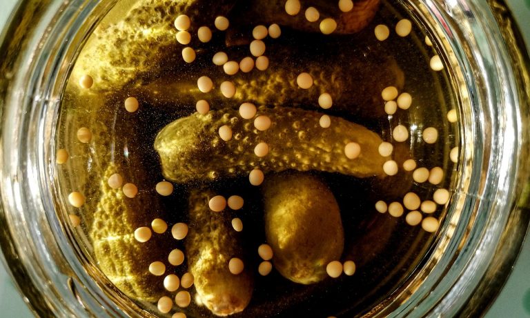 Pickles and mustard seeds in brine jar.