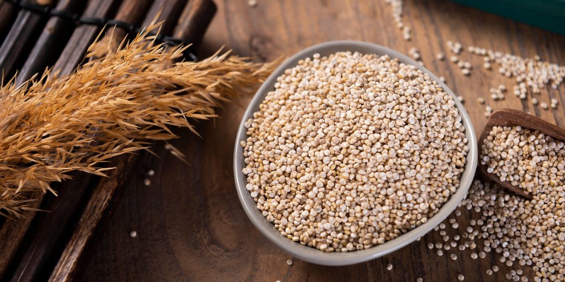 Bowl of quinoa grains on a wooden table.