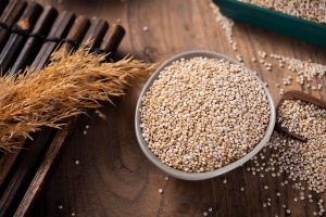 Bowl of quinoa grains on a wooden table.