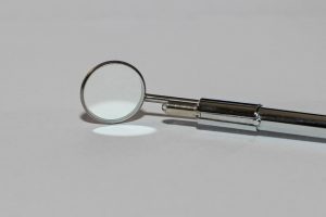 Dental mirror tool on white surface, used in oral check-ups.