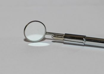 Dental mirror tool on white surface, used in oral check-ups.
