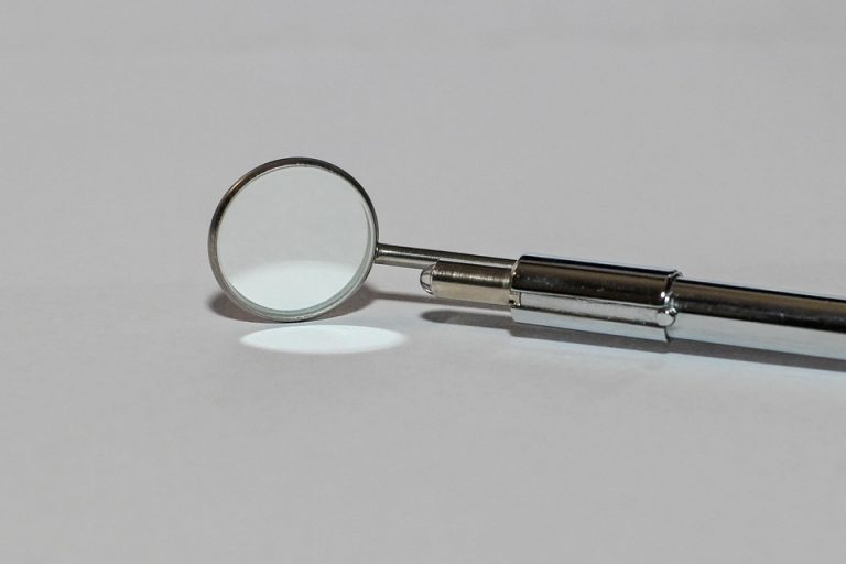 Dental mirror tool on white surface, used in oral check-ups.
