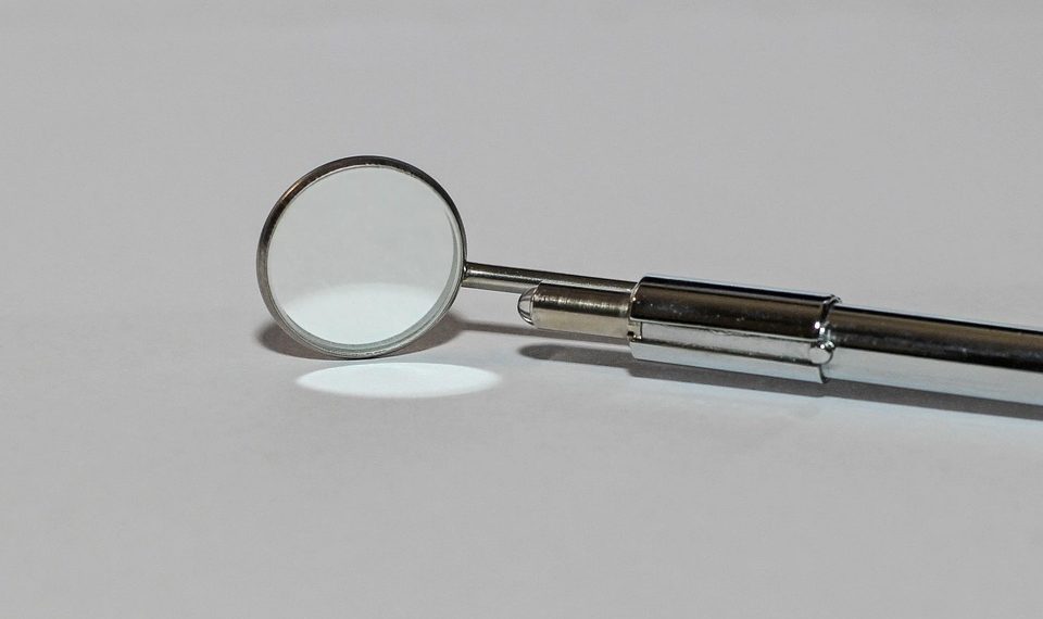 Dental mirror tool on white surface, used in oral check-ups.