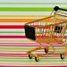 Golden miniature shopping cart on colorful striped background.