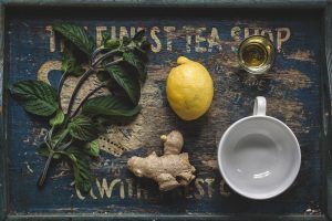 Fresh mint, lemon, and ginger with tea cup on rustic tray.