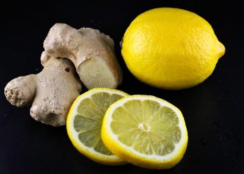 Ginger and fresh lemon slices on black background.