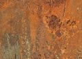 Rusty metal surface texture with orange and brown tones.