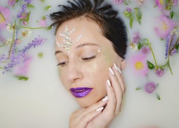 Woman with floral decorations relaxing in milk bath.