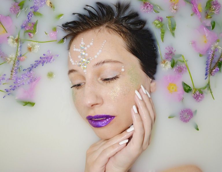 Woman with floral decorations relaxing in milk bath.