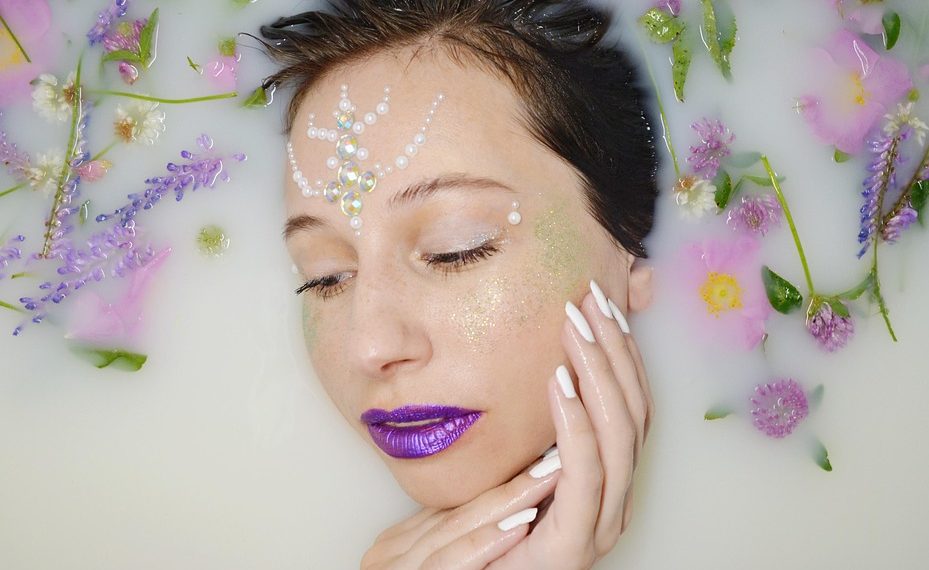 Woman with floral decorations relaxing in milk bath.