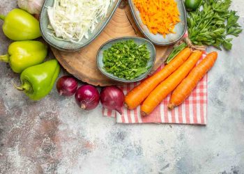 Fresh vegetables and chopped herbs on a rustic kitchen countertop.