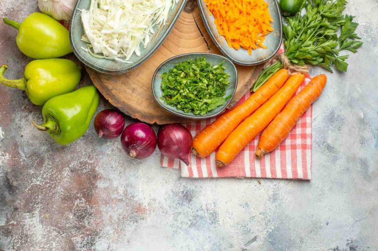 Fresh vegetables and chopped herbs on a rustic kitchen countertop.