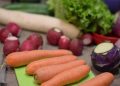 Fresh vegetables including carrots, radishes, and lettuce on a cutting board.