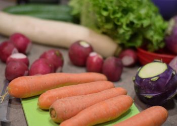 Fresh vegetables including carrots, radishes, and lettuce on a cutting board.
