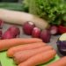Fresh vegetables including carrots, radishes, and lettuce on a cutting board.