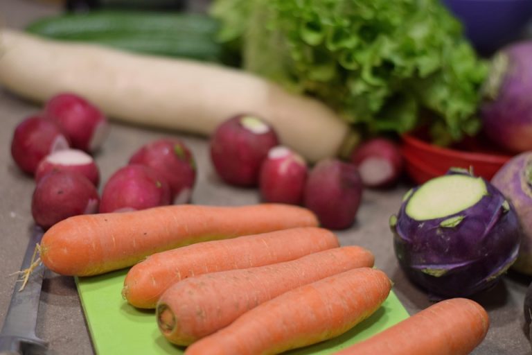 Fresh vegetables including carrots, radishes, and lettuce on a cutting board.