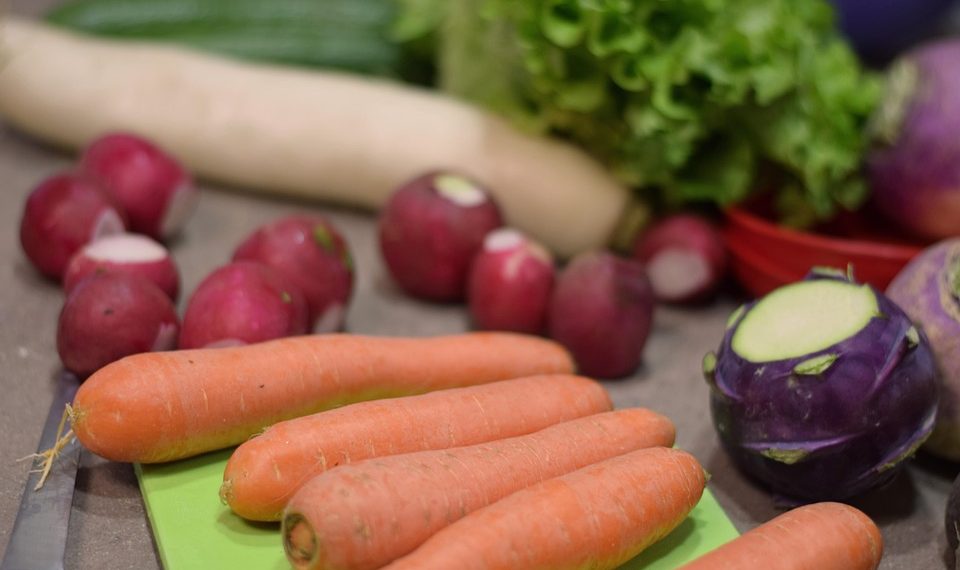 Fresh vegetables including carrots, radishes, and lettuce on a cutting board.
