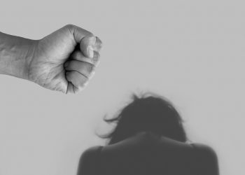Fist raised over a person, highlighting domestic violence.