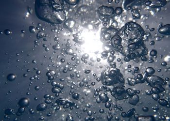 Bubbles rising underwater with sunlight filtering through.