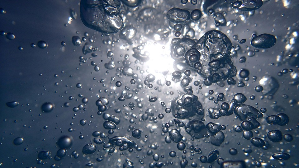 Bubbles rising underwater with sunlight filtering through.