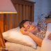 Sleeping woman in comfortable bed under soft lighting.