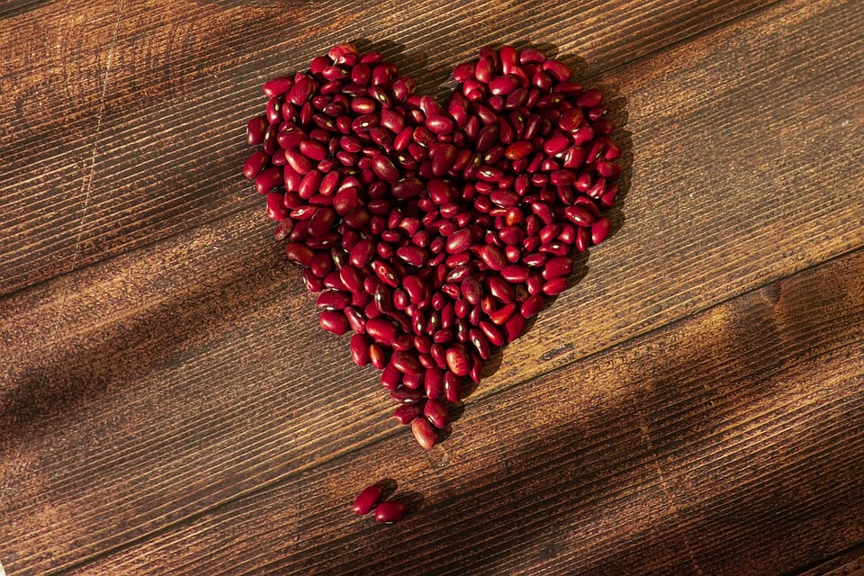 Heart-shaped red kidney beans on wooden surface.