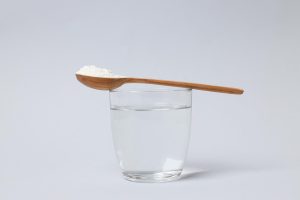 Salt in a wooden spoon with a glass of water