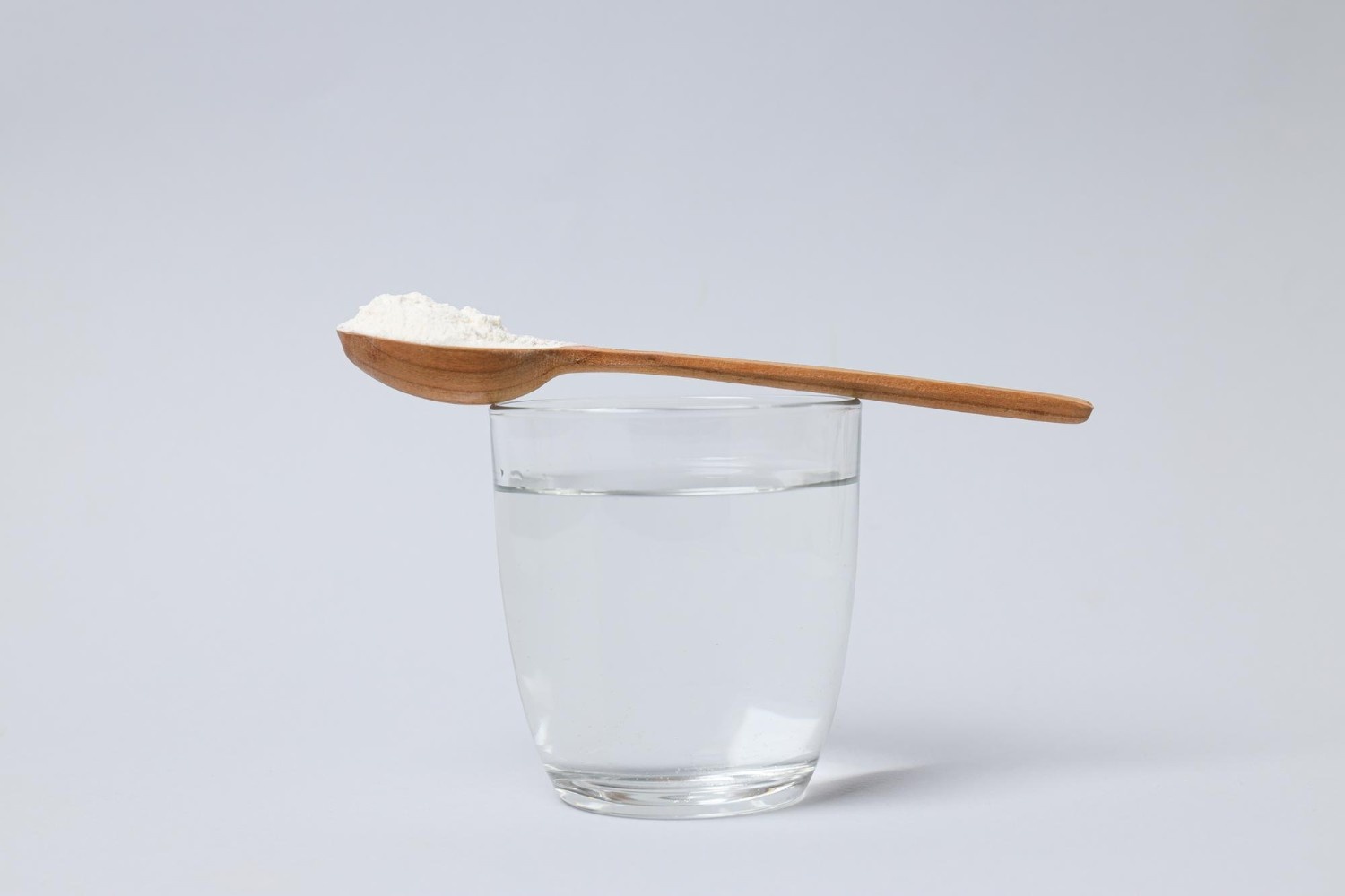 Salt in a wooden spoon with a glass of water