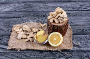 Some ginger with lemon and ginger slices on wood stub, sack cloth and dark