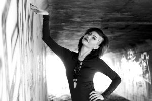 Woman posing confidently in urban setting with graffiti backdrop.