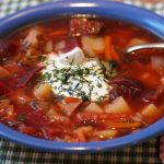 Bowl of borscht topped with sour cream and dill.