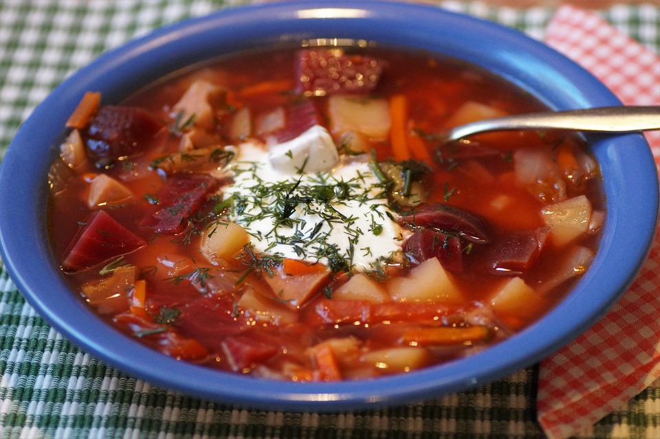 Bowl of borscht topped with sour cream and dill.