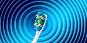 Toothbrush with blue and green bristles on abstract blue spiral background.