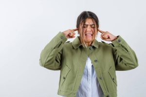 Woman covering her ears on white background