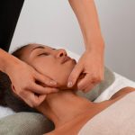 View of woman getting a facial yoga jaw massage to stay young