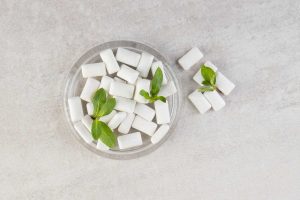 Top view of pile of gums with mint leaves in glass bowl.