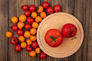 Top view of fresh red tomatoes on a wooden kitchen board with cherry tomato