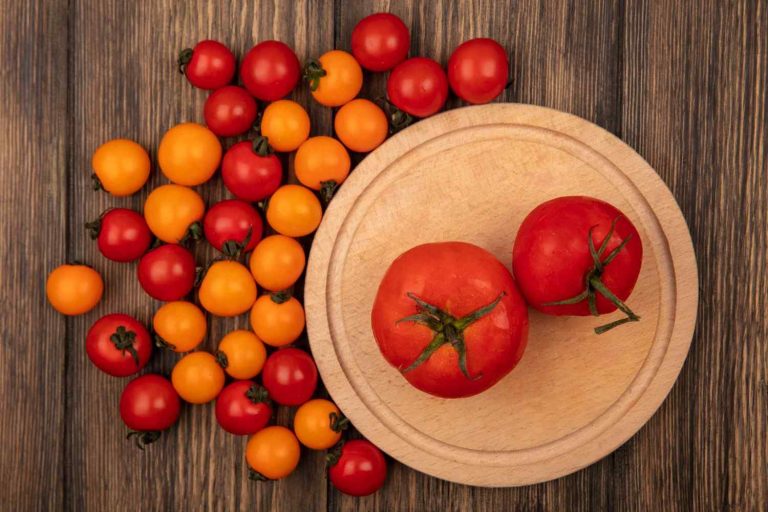 Top view of fresh red tomatoes on a wooden kitchen board with cherry tomato