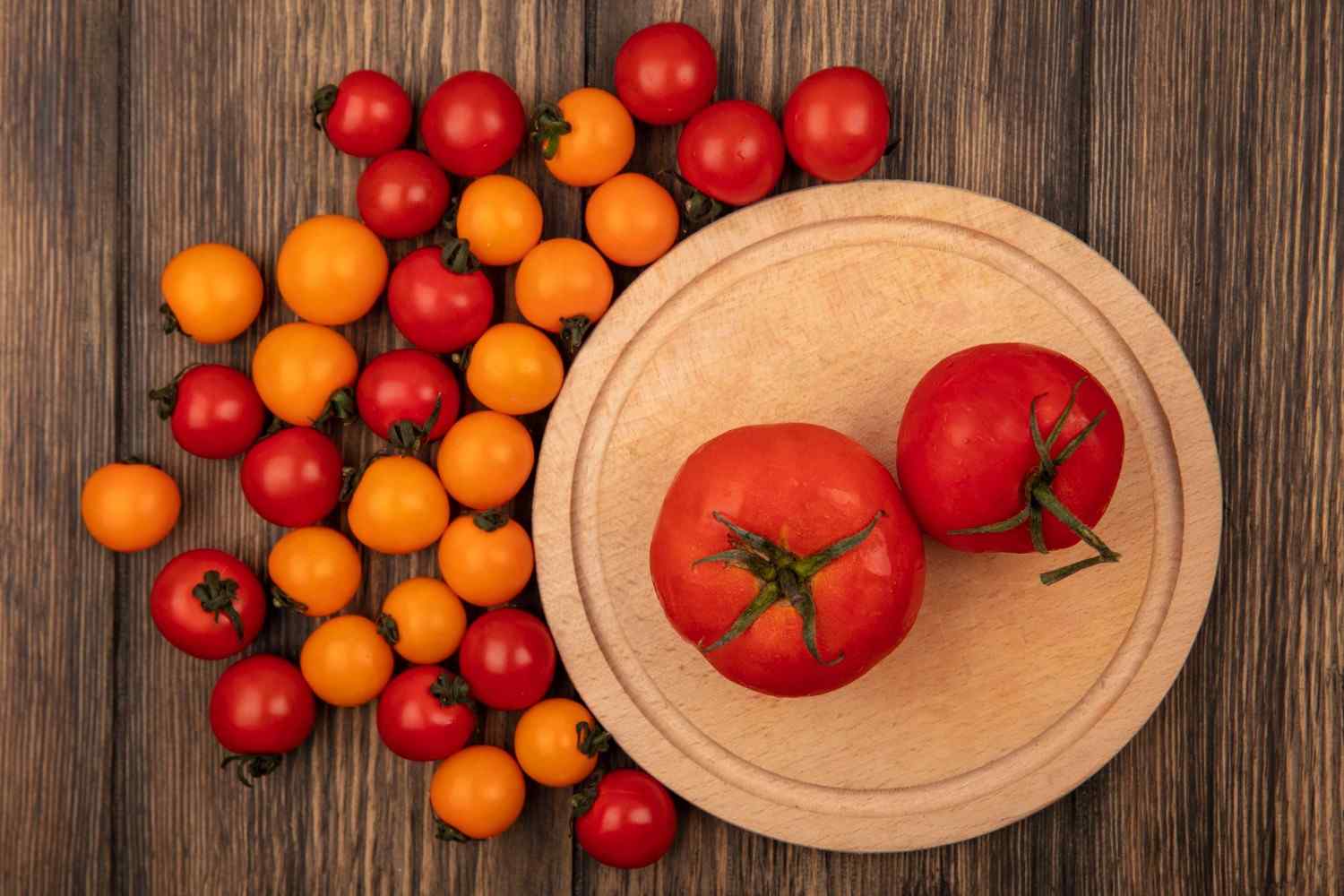 Top view of fresh red tomatoes on a wooden kitchen board with cherry tomato