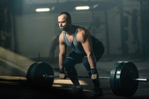 Muscular build man making an effort while weightlifting during cross training i