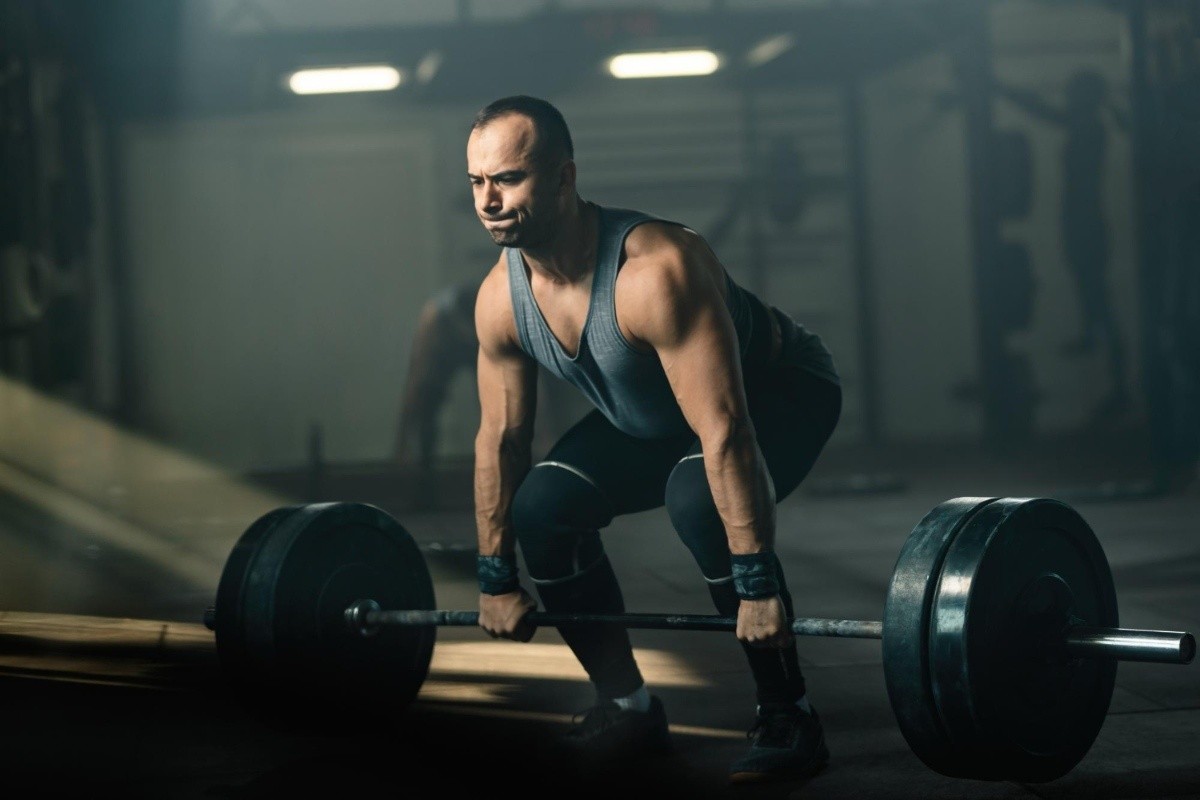 Muscular build man making an effort while weightlifting during cross training i