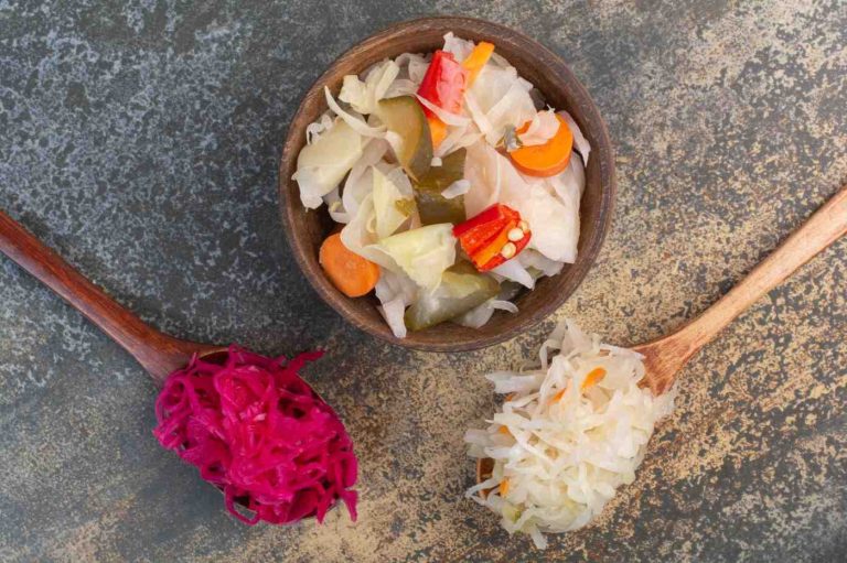 Fermented Sauerkraut Two spoons of cabbage with wooden bowl of salty vegetables
