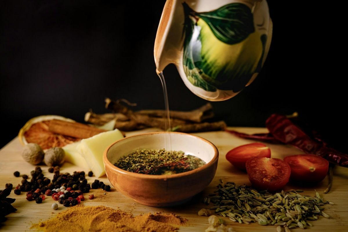 Olive oil being poured into a bowl of herbs
